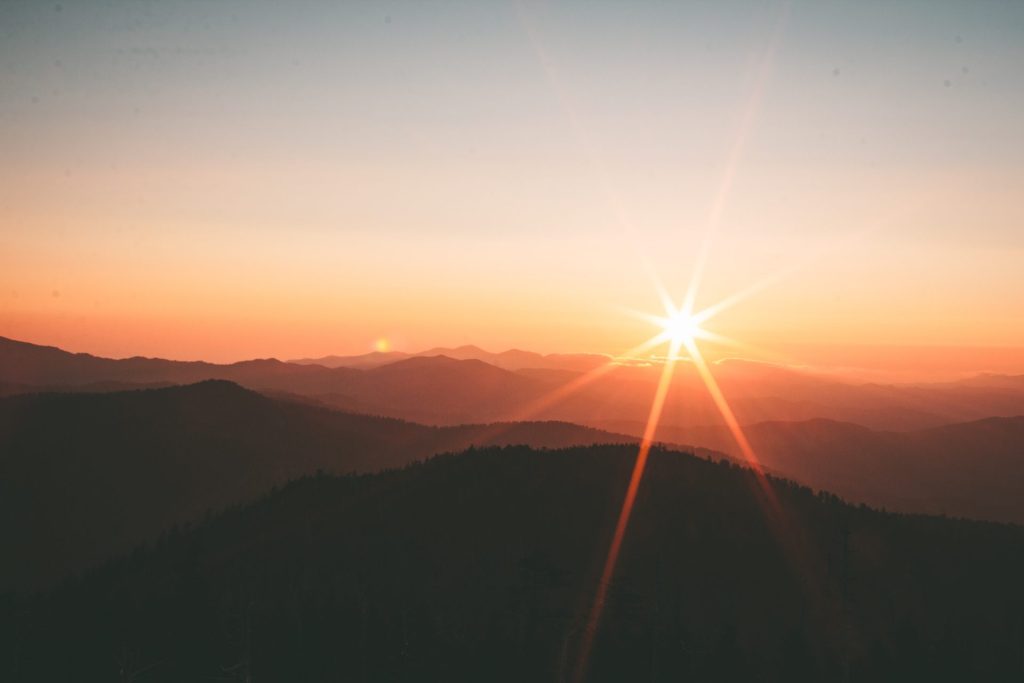 A breathtaking sunrise cresting over majestic mountain peaks, casting a golden glow on the landscape. The image symbolizes a new day, new beginnings, and the promise of growth and longevity, serving as a metaphor for our mission on the 'About Us' page