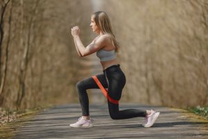 Lady engaging in a workout session using a resistance band, highlighting the benefits of Resistance Training for Skin as part of an anti-aging strategy.