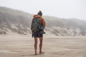 Image captures a serene moment of barefoot walking: a woman on a beach.